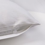Pościel bawełniana w kolorze białym o wymiarach 220x200 cm, z widocznym zapięciem na zamek błyskawiczny. Złożona i leżąca na gładkim, jasnym tle, ukazująca miękką strukturę materiału. Idealna do eleganckiej sypialni.