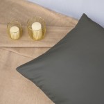 Pościel satyna bawełniana 140x200 w kolorze szarym, leżąca na beżowym tle, z poduszką w gładkim materiale. Obok dwie świece w złotych świecznikach, tworzące elegancką aranżację. Kąt ujęcia frontalny, ukazujący całość zestawu.