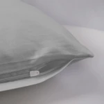 Pościel satyna bawełniana w kolorze popielatym, rozmiar 220x200 cm. Zbliżenie na poszewkę z widocznym suwakiem, wykonana z gładkiego materiału, na jasnym tle.