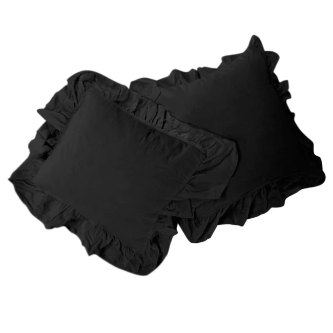 Pościel bawełniana z falbanką 160x200 Stonewashed Exclusive, w kolorze czarnym, rozłożona na płasko. W zestawie dwa poduszki z falbanami po bokach. Tekstura materiału jest miękka, a krawędzie poduszek lekko falowane, co dodaje wyjątkowego charakteru.