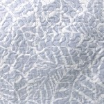 Poszewka na poduszkę 40x40, drukowana w odcieniach jasnego szaro-białego z wzorem przypominającym liście. Ujęcie z bliska, ukazujące fakturę tkaniny oraz delikatne detale wzoru. Tło proste, jednolite, co podkreśla produkt.