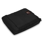Koc bawełniany 150x200 w kolorze czarnym, z frędzlami na końcach, złożony i leżący na jasnym tle. W widoku frontalnym detal z widocznym logo na metce, podkreślający prosty, nowoczesny design. Brak dodatkowych elementów otoczenia.