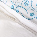 Pościel bawełniana 160x200 Cottonlove w białym kolorze z niebieskim wzorem kwiatowym i spiralnym. Zamek błyskawiczny widoczny na krawędzi poszwy. Rozłożona na płasko, z bliska ukazująca detale tkaniny i wzoru.
