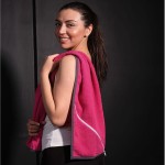 Ręcznik sportowy z kieszonką w kolorze różowym, wykonany z miękkiego materiału, o wymiarach 30x110 cm. Ujęcie z boku, produkt wiszący na ramieniu użytkownika, ukazuje kieszonkę oraz detale wykończenia. Tło ciemne, niezakłócające widoczności produktu.