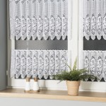 Biała żakardowa zazdrostka o wymiarze 120 cm, zawieszona na oknie, z poziomymi pasami o wzorze w kwiaty. Ujęcie frontalne, w tle parapet z doniczką z rośliną i zestawem dwóch pojemników.