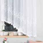 Firana żakardowa Bakaro w kolorze białym, rozmiar 420x160 cm. Produkt wiszący, z delikatnym, kwiatowym wzorem na dole, umieszczony przy oknie. Tło jasne, z ledowym oświetleniem. Widoczne akcesoria: doniczka z rośliną oraz dekoracyjny zegar.