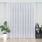 Firana fantazyjna w kolorze białym z subtelnym wzorem ołowianka, wisząca na karniszu, o wysokości 290 cm. Tło jasnoszare, w aranżacji z donicą na roślinę i półką z dekoracjami. Delikatna tekstura materiału, lekko przezroczysta.