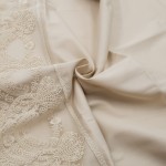 Pościel satyna bawełniana z gipiurą w kolorze beżowym o wymiarach 160x200 cm, leżąca w złożonej pozycji. Widoczne delikatne zdobienia gipiurą oraz gładka, matowa tekstura materiału. Tło jasne, neutralne, podkreślające szczegóły.