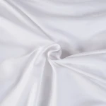 Pościel satyna bawełniana 140x200 w kolorze białym, leżąca na gładkim tle, ukazująca fakturę materiału. Ujęcie w zbliżeniu na szczegóły tkaniny, z widoczną gładkością i połyskiem. Brak dodatkowych wzorów i napisów.