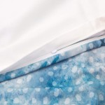 Pościel satyna bawełniana 220x200 Luxury Premium Belize w kolorze niebieskim i białym. Zbliżenie na zamek błyskawiczny, pokazujący wzór w jasnoniebieskie plamy na dolnej części poszwy. Górna część poszwy biała, układa się leżąco na płasko.