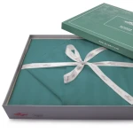Pościel bambusowa satyna bawełniana 180x200 w kolorze turkusowym, z prążkowanym wzorem. Produkt rozłożony na podłożu, w eleganckim opakowaniu z białą kokardą. Widoczne logo DARYmex na opakowaniu. Zestaw zawiera poszewki na poduszki oraz poszwę na kołdrę.