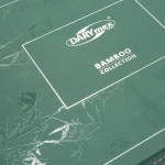 Zielone opakowanie pościeli bambusowej z logo DARYmex. Na widocznej górnej części napis BAMBOO COLLECTION w białym kolorze, otoczone przez delikatny wzór liści bambusa. Tekst jest czytelny, a tło matowe.