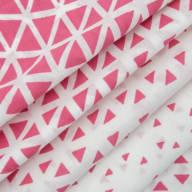 Pościel bawełniana 200x220 Cottonlove Exclusive Milano w kolorze różowym z geometrycznym wzorem białych trójkątów. Materiał gładki, złożony, ukazujący fakturę tkaniny. Zdjęcie wykonane z bliska, w układzie leżącym.