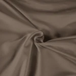 Pościel satyna bawełniana 220x200 w kolorze sepia, z gładką, matową fakturą. Widok z góry, materiał lekko pomarszczony, podkreślający jego miękkość i elegancję. Produkt leży rozłożony na płaskiej powierzchni, bez widocznych detalów.