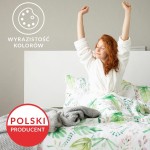 Pościel bawełniana 160x200 w kratkę w odcieniach szaro-białym, z wzorem roślinnym. Na łóżku z białą narzutą, z szarym kocem. Ujęcie z boku, z wyciągniętymi rękami kobiety w białym szlafroku. Tło jednolite, w neutralnym kolorze.