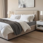 Prześcieradło jersey z elastanem, antracytowe, naciągnięte na materac o wymiarach 140x200 cm. Ułożone na łóżku z jasnymi poduszkami i dekoracyjnym kocem w odcieniach szarości. Tło z neutralnymi kolorami, minimalistyczny wystrój sypialni.