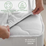 Białe prześcieradło jersey z elastanem, z gumką, rozłożone na materacu o grubości 25 cm. Na zdjęciu widoczna ręka zakładająca prześcieradło, w lewym górnym rogu ikony bardzo elastyczne i rozciągliwe oraz wytrzymałe. Tło neutralne.