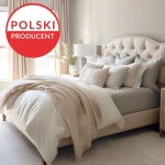 Prześcieradło jersey z elastanem w kolorze antracyt, rozmiar 180x200, leży na łóżku w jasnej sypialni. Produkt jest rozłożony, ukazując gładką teksturę materiału.
