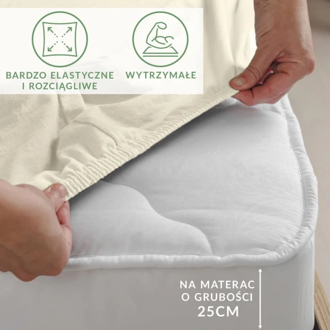 Prześcieradło jersey z elastanem w kolorze ekologicznym, z gumką, rozłożone na materacu o grubości 25 cm. Zbliżenie na materiał, ukazujące jego elastyczność. Widoczne napisy: bardzo elastyczne i rozciągliwe oraz wytrzymałe.