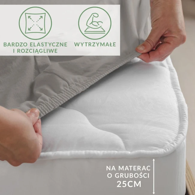 Prześcieradło jersey z elastanem w kolorze popiel, naciągnięte na materac, prezentujące elastyczną gumkę oraz wyjątkową miękkość. Widoczne oznaczenia sugerujące zastosowanie na materac o grubości 25 cm. Zbliżenie na fakturę tkaniny.