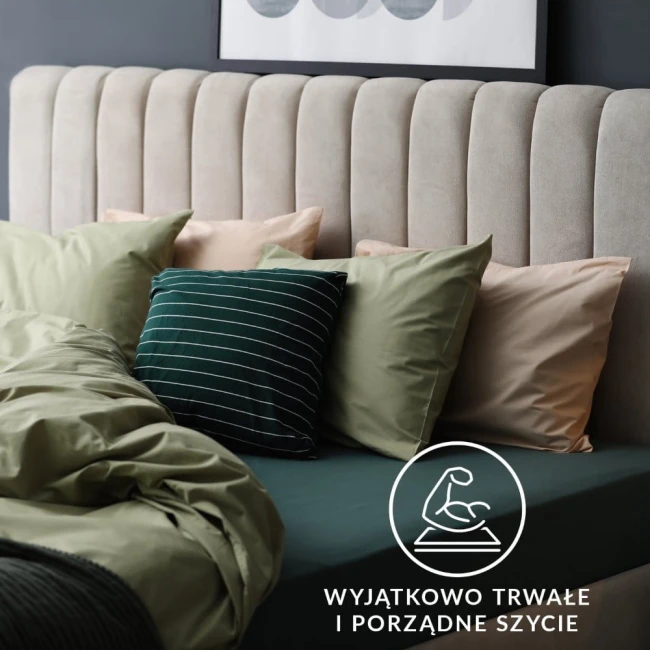 Prześcieradło jersey z gumką 90x200 w kolorze niebieskim, rozłożone na łóżku, w komplecie z poduszkami w różnych odcieniach. Ujęcie frontalne, prezentujące fakturę materiału i gumkę. Tło proste, w kolorze szarym, z dekoracyjnym zagłówkiem.