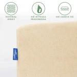 Prześcieradło jersey z gumką w jasnym beżu, leżące płasko. Widoczny materiał, który nie wymaga prasowania i nie gniecie się. Z prawej strony niebieska metka z logo producenta. Tło jasne, jednolite.