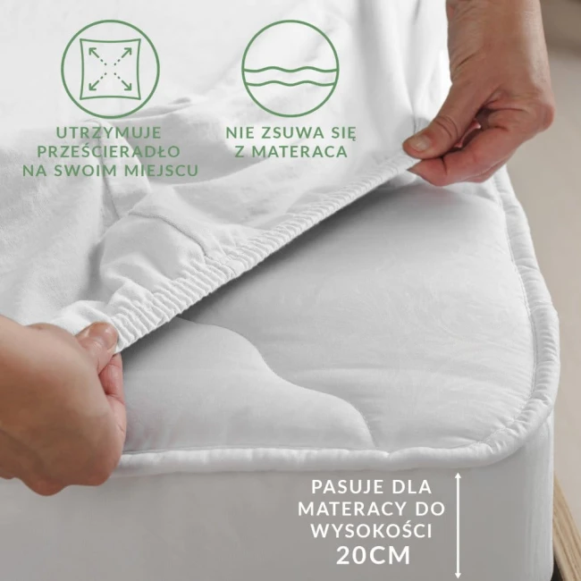 Prześcieradło jersey z gumką w kolorze jasnego różu, rozłożone na materacu. Ujęcie z boku, pokazujące elastyczną gumkę, która utrzymuje je na miejscu.