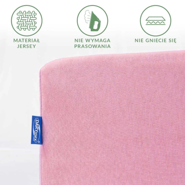 Prześcieradło jersey z gumką w kolorze jasnego różu, w układzie leżącym. Widoczna etykieta producenta. Materiał nie wymaga prasowania i nie gniecie się, tekstura gładka. Produkt o wymiarach 60x120 cm, na jednolitym tle.