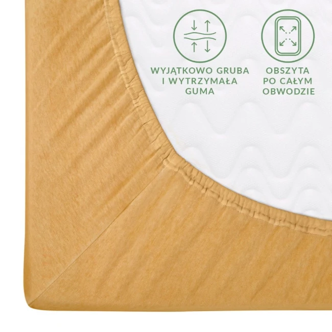 Prześcieradło jersey z gumką 90x200 w kolorze musztardowym, z widoczną, elastyczną i grubą gumą obszywającą cały obwód. Zbliżenie na róg prześcieradła ukazuje jego miękką fakturę i właściwości dopasowujące. Tło białe.