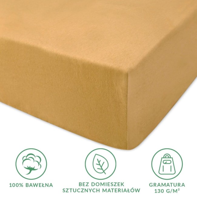 Prześcieradło jersey z gumką w kolorze musztardowym, wykonane z 100% bawełny, o gramaturze 130 g/m². Ułożone poziomo, ukazuje gładką fakturę i wytrzymałe wykończenie brzegów. Widoczne napisy informacyjne o składzie, braku domieszek i gramaturze.