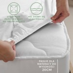 Prześcieradło jersey z gumką w kolorze musztardowym, elastyczne, dopasowane do materaca o wysokości do 20 cm. Ujęcie z boku, ręka trzymająca materiał. Widoczny gładki splot dzianiny, gumka utrzymująca prześcieradło na miejscu, bez zagnieceń.