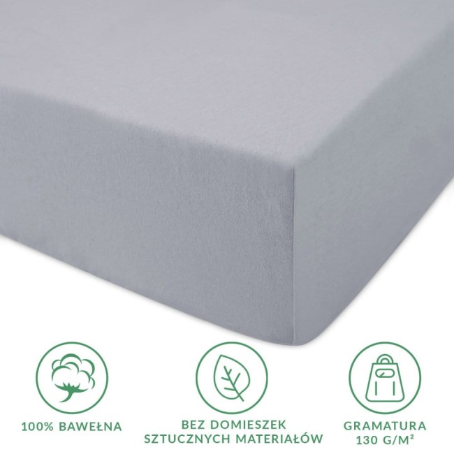 Prześcieradło jersey z gumką w kolorze popielatym, rozmiar 180x200 cm, leżące na boku. Wykonane w 100% z bawełny, posiada atrakcyjną, gładką fakturę. Widoczne informacje o gramaturze 130 g/m² oraz brak domieszek sztucznych materiałów.