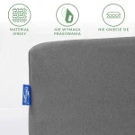 Prześcieradło jersey z gumką 140x200 w kolorze szarym, wykonane z elastycznego materiału, leżące na gładkiej powierzchni. Widoczna niebieska metka z logo.