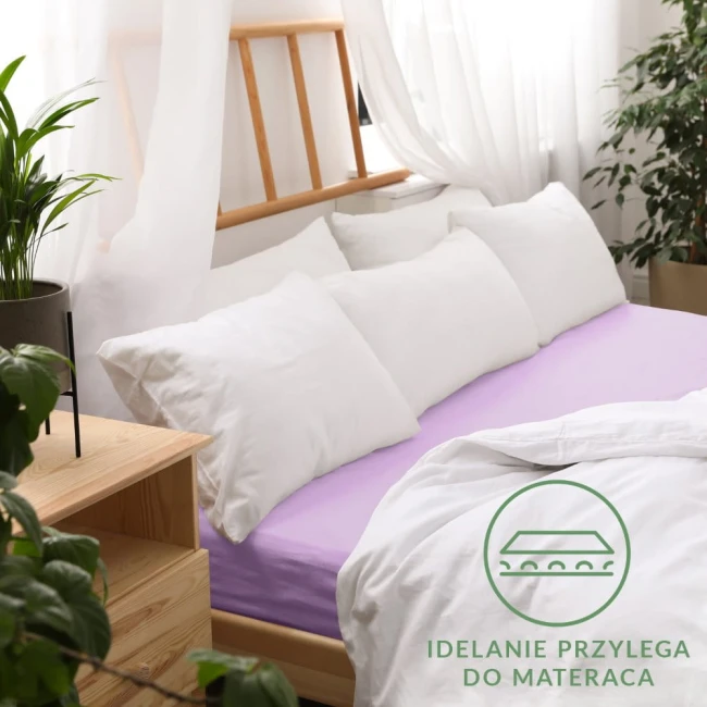 Prześcieradło jersey z gumką 180x200 w kolorze wrzosowym, leżące na łóżku, z białymi poduszkami w tle. Widoczna gładka faktura materiału, idealnie przylegająca do materaca.
