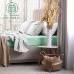 Prześcieradło frotte z gumką 180x200 w kolorze morskim leży na łóżku, nakryte białą pościelą. Produkt jest rozłożony na materacu, doskonale dopasowany do krawędzi. W tle widoczny jest stolik nocny z białą wazonem i suszonymi kwiatami.