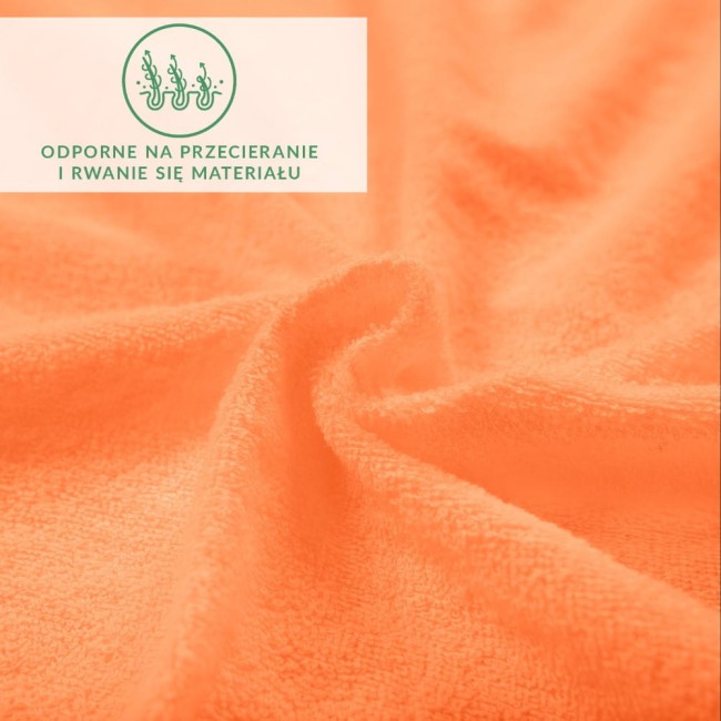 Prześcieradło frotte z gumką w kolorze łososia o wymiarach 200x220 cm. Materiał o teksturowanej powierzchni, ukazujący delikatne zagięcia. Widoczna etykieta informująca o odporności na przecieranie i rwanie materiału.