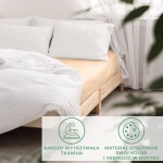 Prześcieradło satynowe z gumką 90x200 w jasnym beżu, rozłożone na łóżku, w towarzystwie białych poduszek. Tło jasne, z naturalnym oświetleniem. Widoczne informacje o trwałości tkaniny i utrzymaniu koloru.