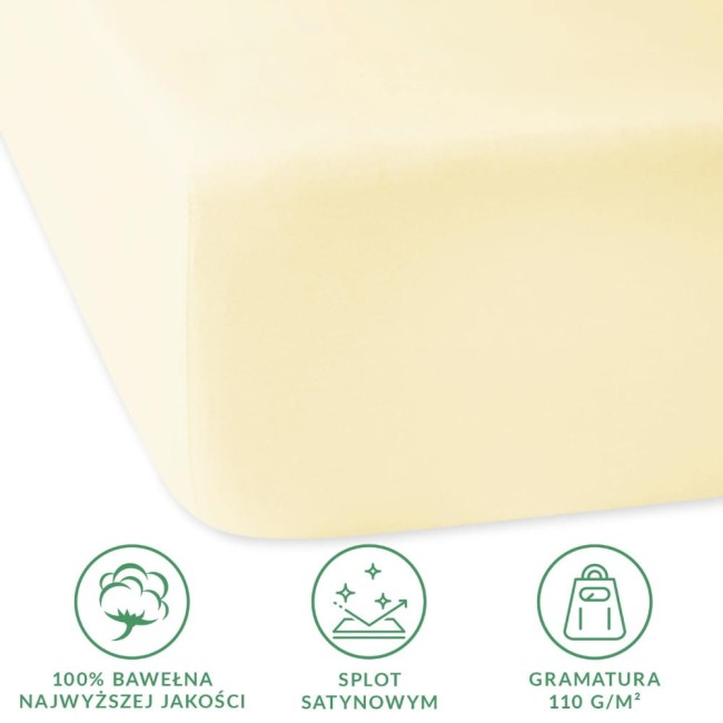 Prześcieradło satynowe z gumką 90x200 w kolorze kremowym, wykonane z 100% bawełny. Zbliżenie na krawędź, ukazuje gładką fakturę. Widoczne symbole dotyczące materiału i gramatury. Produkt leży na jednolitym tle.