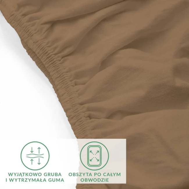 Prześcieradło jersey z elastanem 160x200 w kolorze brązowym, leżące na białym tle. Zbliżenie pokazuje elastyczną gumkę obszytą po całym obwodzie, co zapewnia stabilność. Tkanina jest gładka, z lekko matową strukturą. Widoczne symbole jakości.