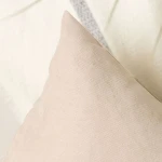Poszewka dekoracyjna 40x40 cm w kolorze kremowym, gładka faktura, leżąca na jasnym tle. Ujęcie w zbliżeniu, ukazujące detale materiału i kształt poduszki. Tło neutralne, minimalistyczne, pozwalające na łatwe dopasowanie do wnętrza.