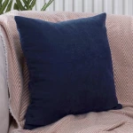 Poszewka dekoracyjna 40x40 w kolorze granatowym, gładka, umieszczona na jasnym, wzorzystym tle. Produkt leży na poduszce, podkreślając teksturę materiału. Brak widocznych napisów, logo lub dekoracji.