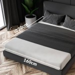 Prześcieradło satynowe bez gumki w kolorze czarnym, o wymiarach 160x220 cm, leżące na łóżku. Widoczny detal tekstury materiału, na tle szarej poduszki oraz ciemnego zagłówka. Oświetlenie naturalne z okna, drewniana podłoga w tle.