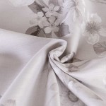 Pościel satyna bawełniana 160x200 Exclusive Paredes w kolorze szaro-beżowym z delikatnym kwiatowym wzorem. Materiał o gładkiej fakturze, złożony w kształt fałd. Widoczne detale wzoru w odcieniach beżu i szarości, co nadaje elegancki wygląd.