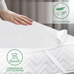 Ochraniacz na materac 160x200 cm w kolorze białym, pokazany z bliska na rozłożonym materacu. Widać gładką, teksturowaną powierzchnię, a także uchwyconą rękę na produkcie. Widoczne są elastyczne paski mocujące. Tło w neutralnych odcieniach.
