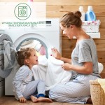 Kobieta w szarej koszulce siedzi na podłodze obok białej pralki, trzymając biały ręcznik. Obok niej bawi się mała dziewczynka w piżamie w paski, uśmiechając się. Tło w drewnianych panelach, z widocznymi detergentami i koszem na pranie.