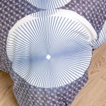 Pościel satyna bawełniana 160x200 w kolorze białym z niebieskimi okrągłymi wzorami i delikatnymi liniami. Złożona na podłożu, z widoczną fakturą materiału. Zdjęcie pokazuje zbliżenie na detal wzoru, na jasnym tle.