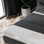 Prześcieradło frotte z gumką w kolorze różu perłowego, rozmiar 90x200 cm, leżące na łóżku. Na zdjęciu widoczna faktura materiału, gumka zabezpieczająca oraz wymiary produktu wskazane strzałkami. Otoczenie to nowoczesna sypialnia z drewnianą podłogą.