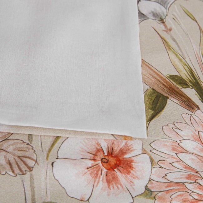 Pościel bawełniana 200x220 Cottonlove Exclusive Sidelya w beżowe kwiaty, złożona na jasnym tle. Widoczny fragment poszewki w białym kolorze, z subtelną teksturą. Kwiaty w odcieniach różu i zieleni, delikatny wzór na tle beżu.