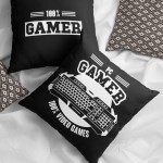 Poduszka 40x40 cm w kolorze czarnym z białym nadrukiem 100% GAMER i motywem klawiatury. Ułożona na jasnym podłożu obok wzorzystej poduszki, ukazana z góry, z wyraźnymi detalami nadruku oraz teksturą materiału.