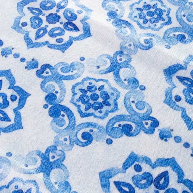 Ścierka kuchenna Ocean Blue w kolorze białym z niebieskim wzorem kwiatowym i spiralnym. Ułożona płasko, zbliżenie na detale wzoru, przedstawiającego różne odcienie niebieskiego. Materiał tekstylny, idealna do użytku kuchennego. Wymiary: 38x60 cm.